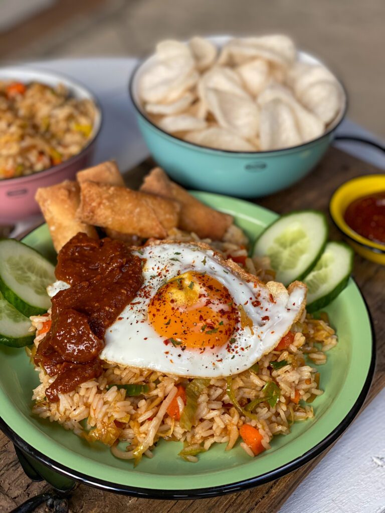 nasi zonder pakjes en zakjes geserveerd met zelfgemaakte pindasaus, mini loempia's, plakjes komkommer en kroepoek.