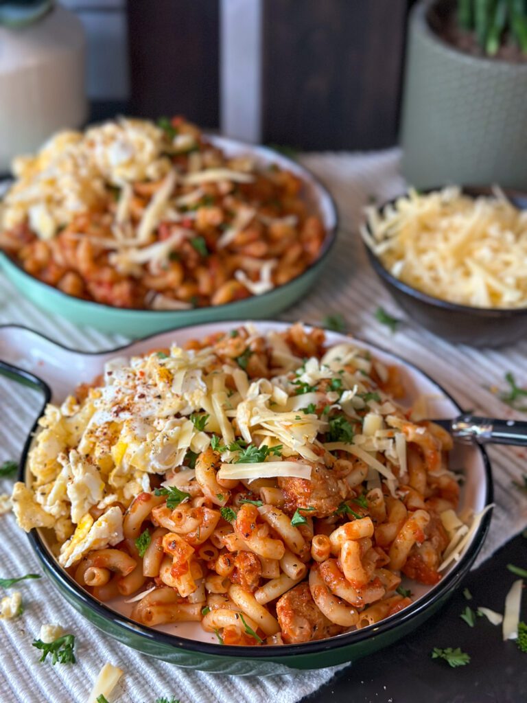 snelle pasta avondmaaltijd geschikt voor het hele gezin, geserveerd op een rond bord met geraspte kaas en roerei