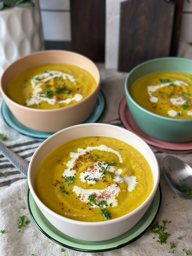 bloemkoolsoep recept met kerrie geserveerd met scheutje kookroom en verse peterselie, in witte kom