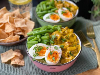 kip kerrie met rijst geserveerd met sperzieboontjes en zacht gekookt ei en een schaaltje kroepoek