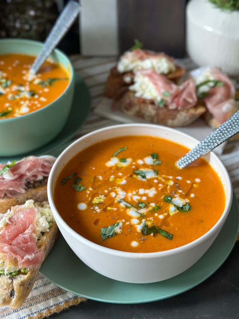 verse tomatensoep in een kom geserveerd met verse basilicum een een drizzle room