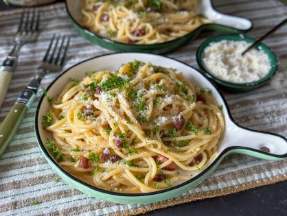 Italiaanse pasta carbonara met een romige saus, versgemalen zwarte peper en geraspte kaas.