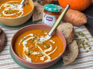 pompoensoep met zoete aardappel en harissa en extra pompoenpitten eroverheen bestrooid.