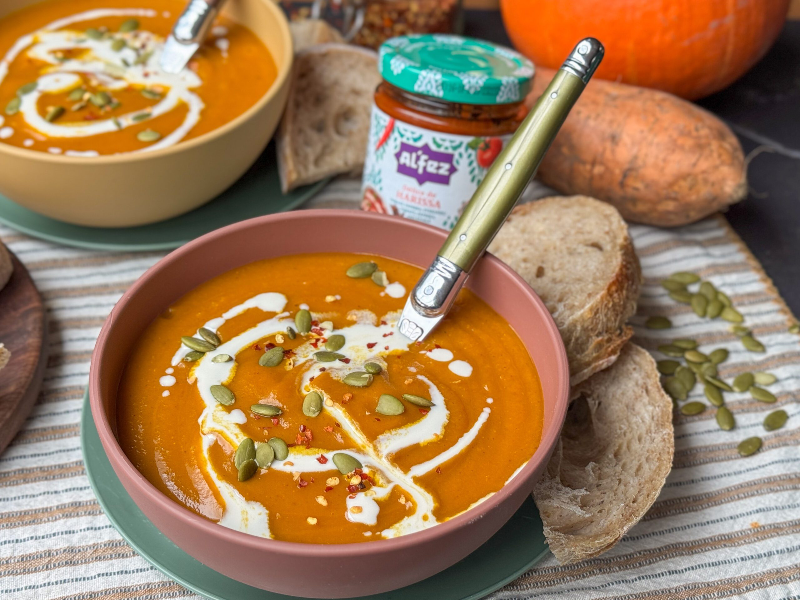 pompoensoep met zoete aardappel en harissa en extra pompoenpitten eroverheen bestrooid.