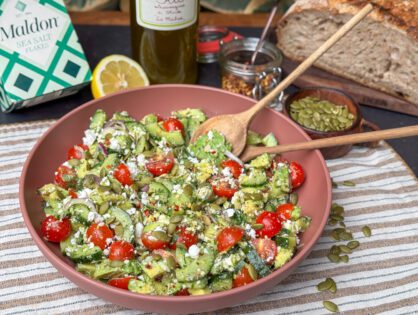 een schaal met een gezonde salade met avocado, feta, tomaatjes en kruidige Italiaanse dressing.