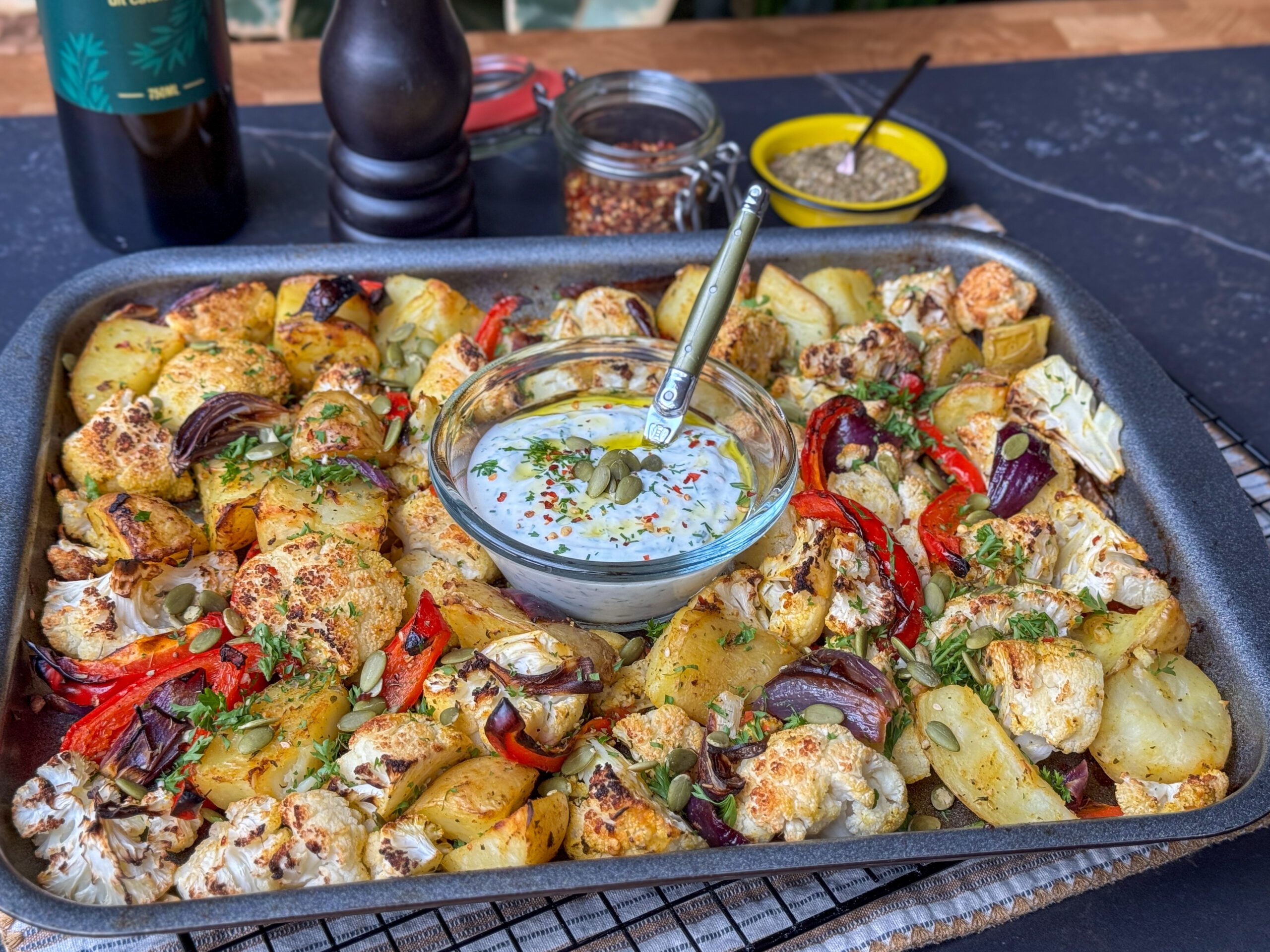 Gezonde en makkelijke traybake met bloemkool en aardappelen, perfect geroosterd op een bakplaat met specerijen en een frisse yoghurt dip erbij.