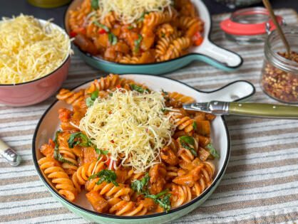 Een heerlijk bord makkelijke pasta met aubergine en tonijn, gegarneerd met verse basilicum en geraspte kaas, klaar om van te genieten."