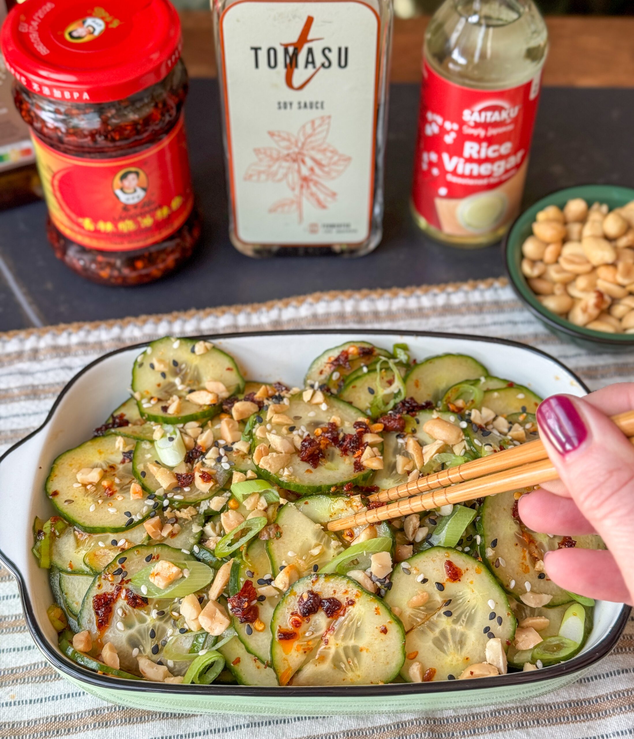 Aziatische komkommersalade met pinda’s en crispy chili olie geserveerd in wit schaaltje