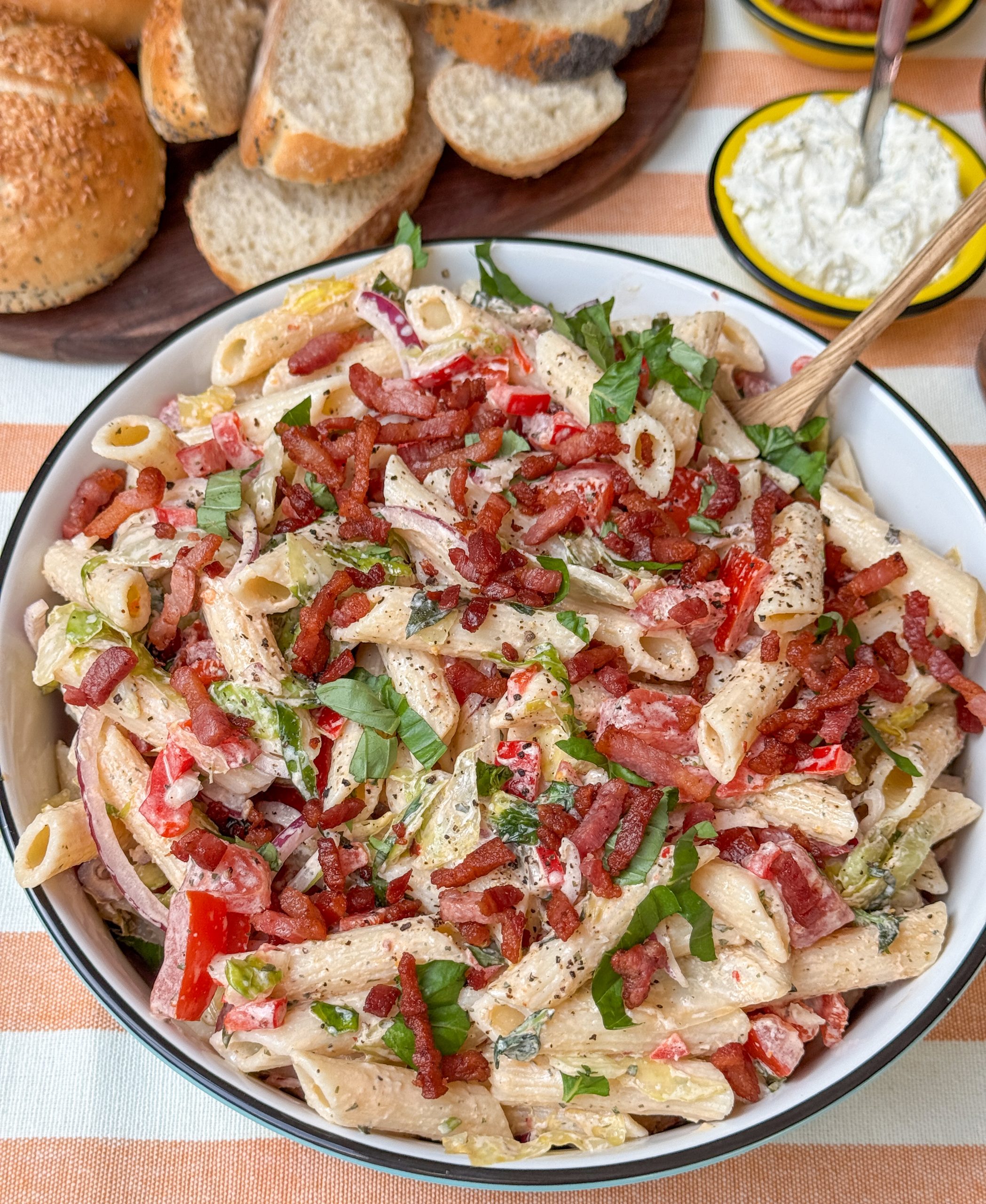 BLT pastasalade recept, zomerse pastasalade met spek, tomaat en romige dressing op tafel geserveerd