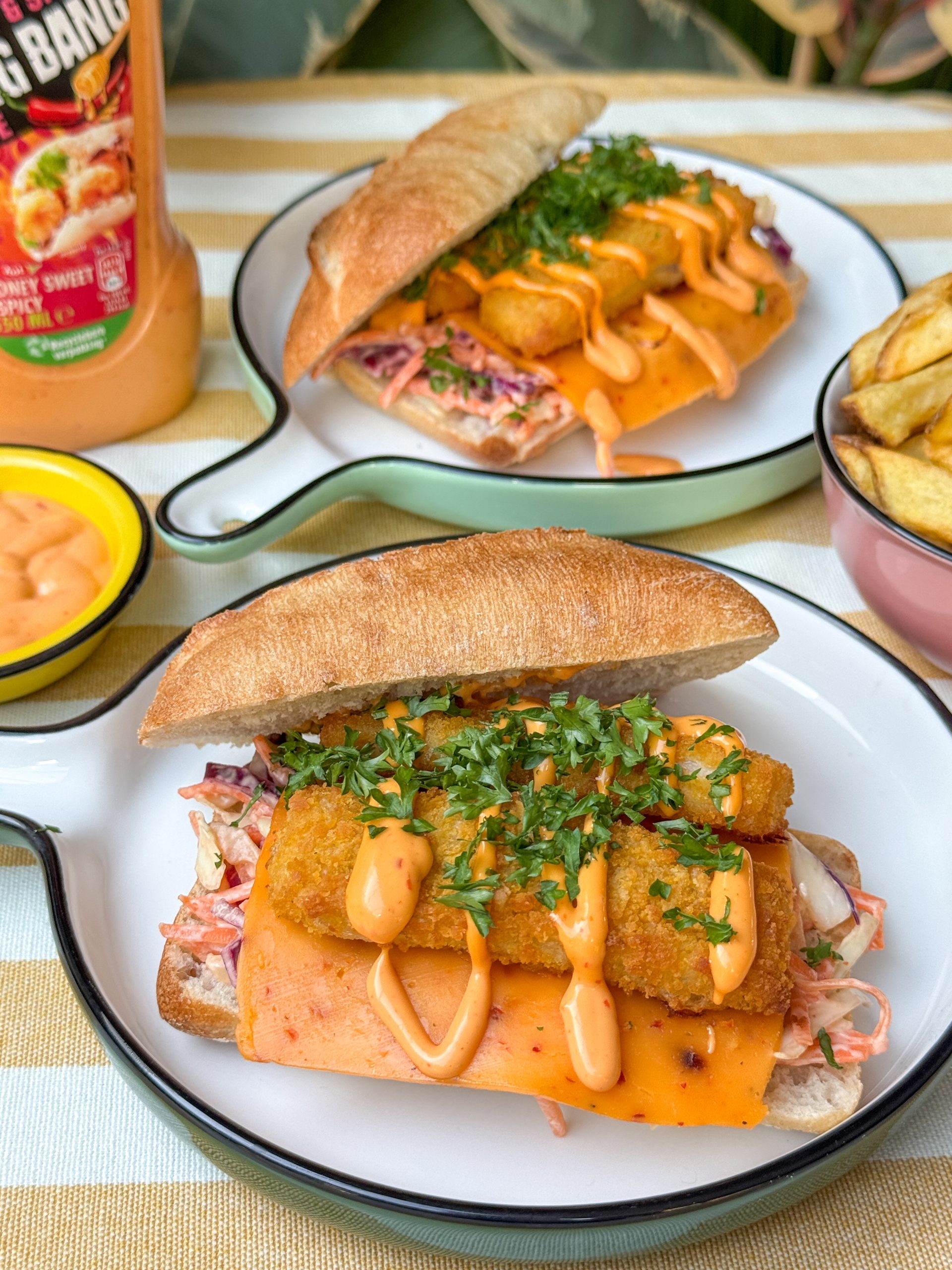 broodje vissticks met bang bang saus - geserveerd met coleslaw en ceddar op rond wit bord