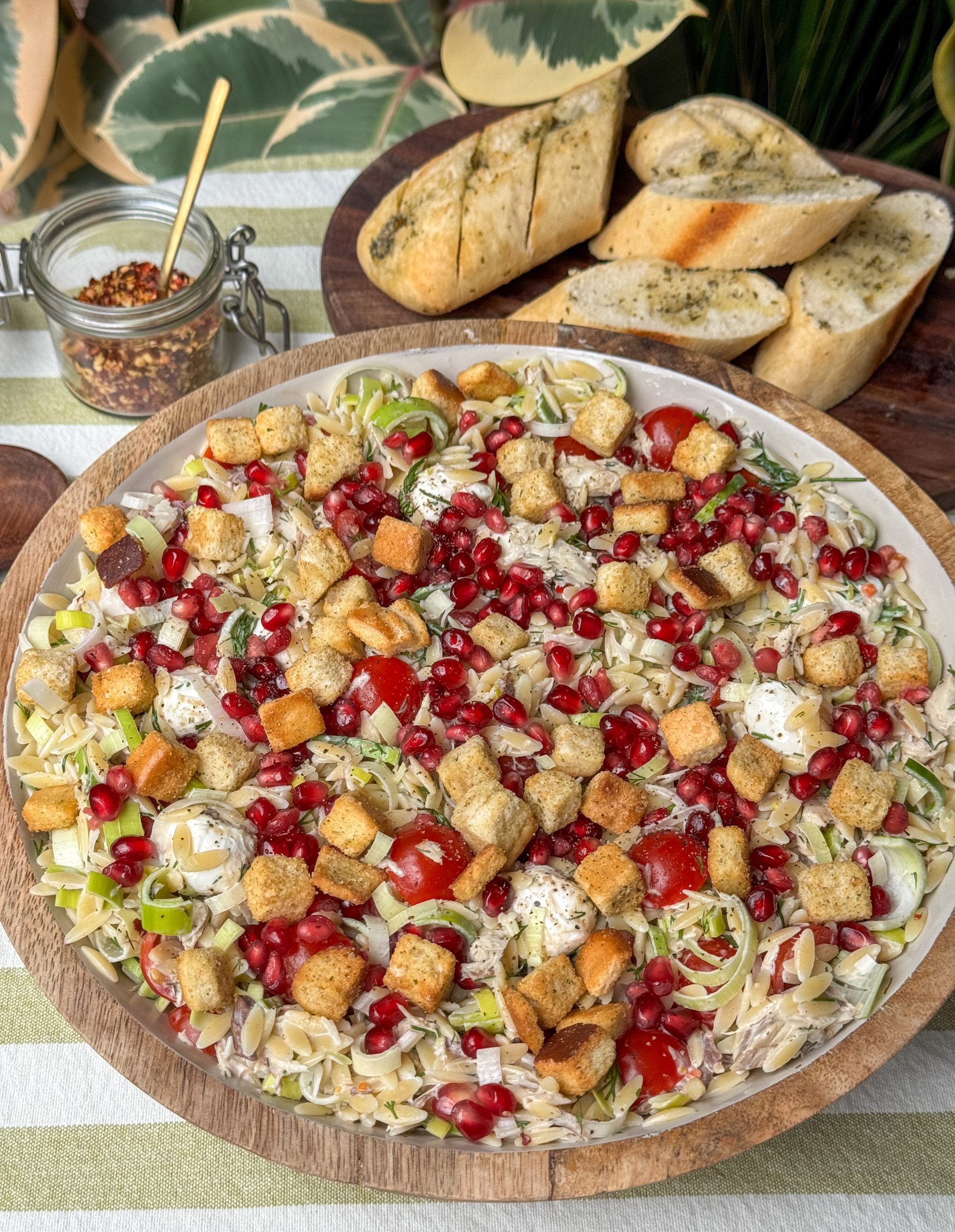 orzo salade met makreel, granaatappelpitjes, prei, tomaatjes en croutons geserveerd in een grote schaal, recept van Familie over de Kook