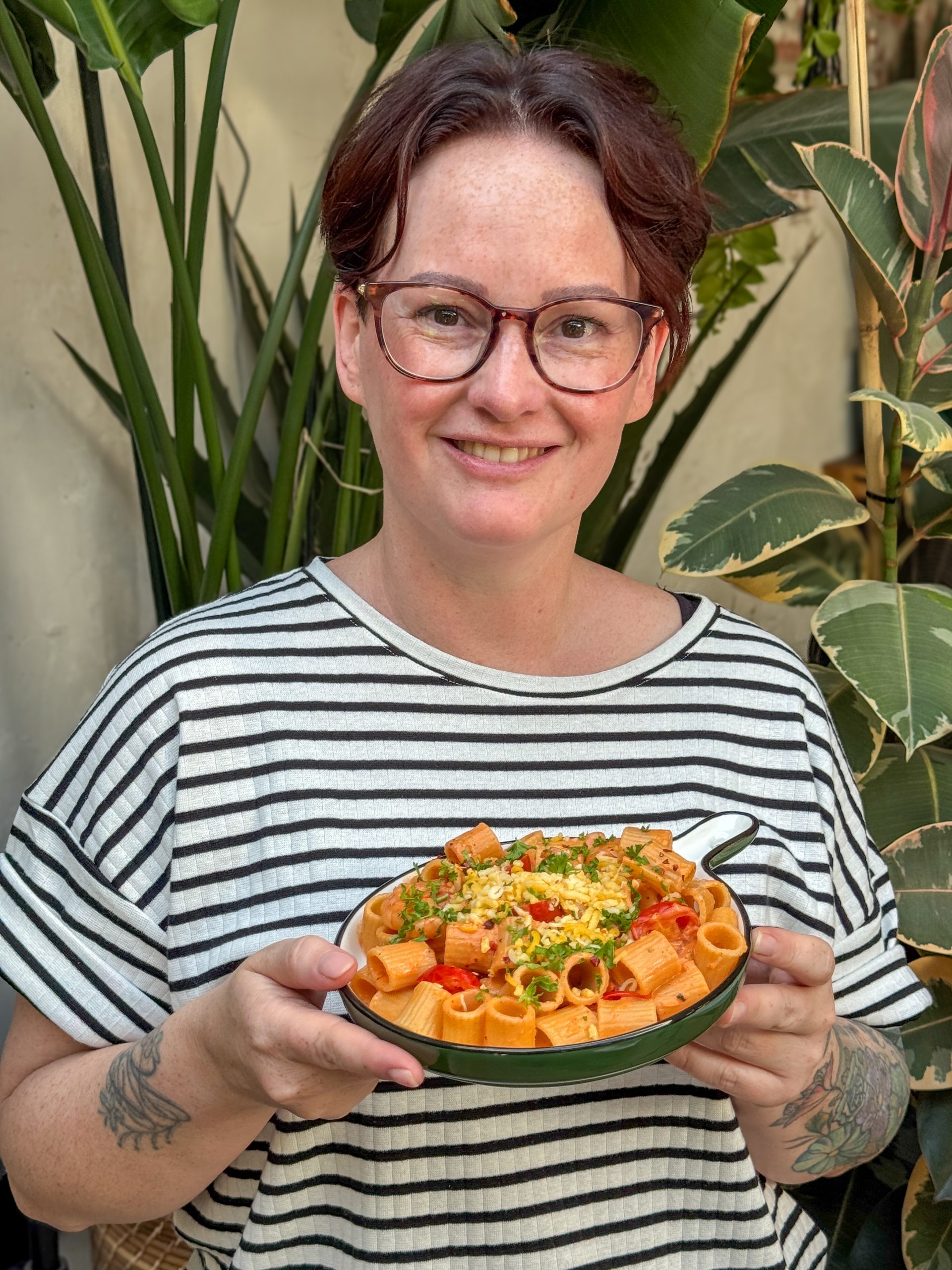 pasta met garnalen recept - marie louise serveert romige pasta met tomatensaus en cajungarnalen op rond bord