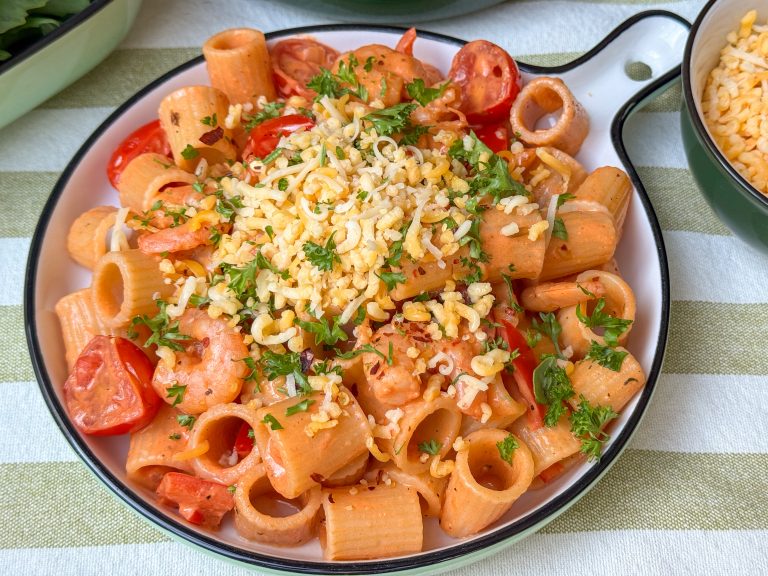 pasta met garnalen recept - in romige tomatensaus geserveerd met kaas en peterselie op rond bord