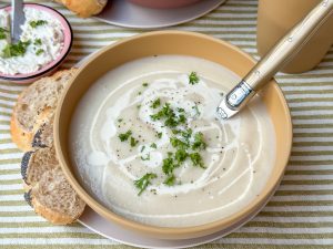 bloemkoolsoep recept - romige soep geserveerd in lichtgele kom met verse peterselie