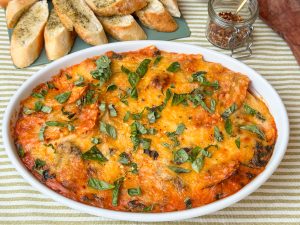 ravioli ovenschotel met spinazie in romige tomatensaus, in witte ovenschaal met gesmolten kaas