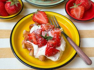 wafels met aardbeien gemarineerd met limoensap en munt toetje op geel bord geserveerd met crème fraîche