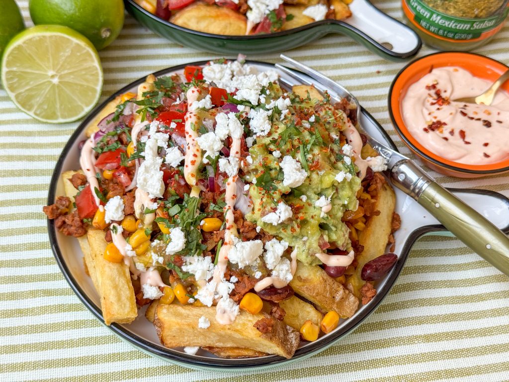 Mexicaanse loaded fries recept met sriracha mayonaise, feta, pico de gallo en en guacamole op een wit bord