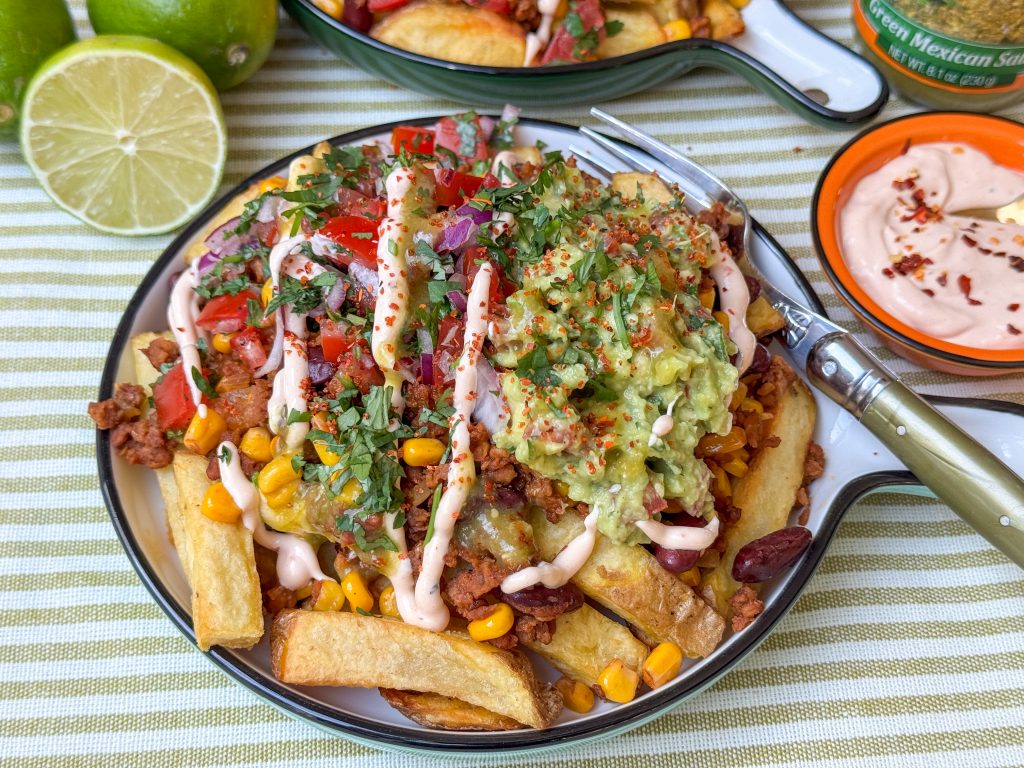 Mexicaanse loaded fries recept met sriracha mayonaise, feta, pico de gallo en en guacamole op een wit bord