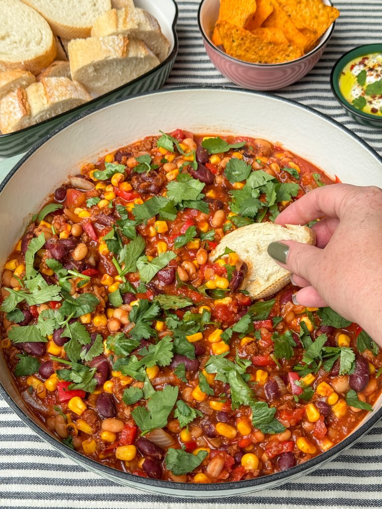 close up vegetarische chili con carne in pan met bonen, mais, stukje stokbrood wordt ingedipt