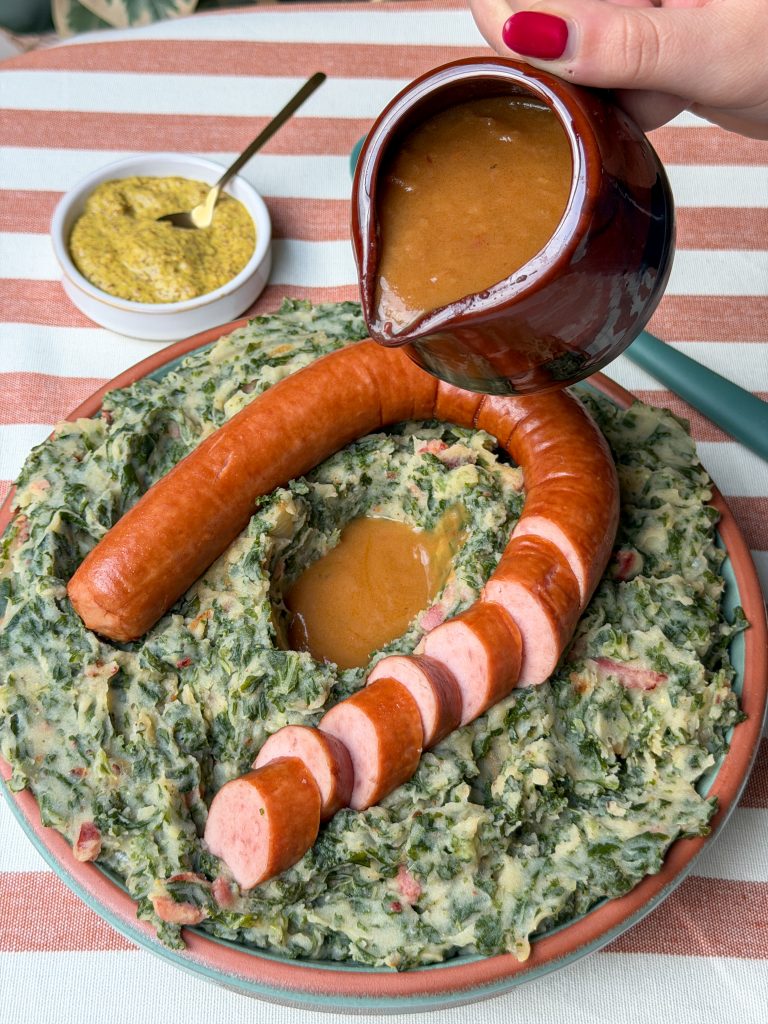 Jus wordt over de boerenkoolstamppot met rookworst gegoten voor extra smaak.