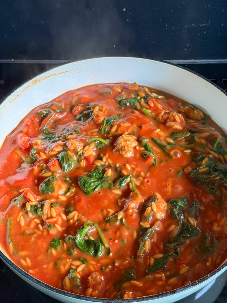 Gezeefde tomaten en bouillon toevoegen aan de orzo
