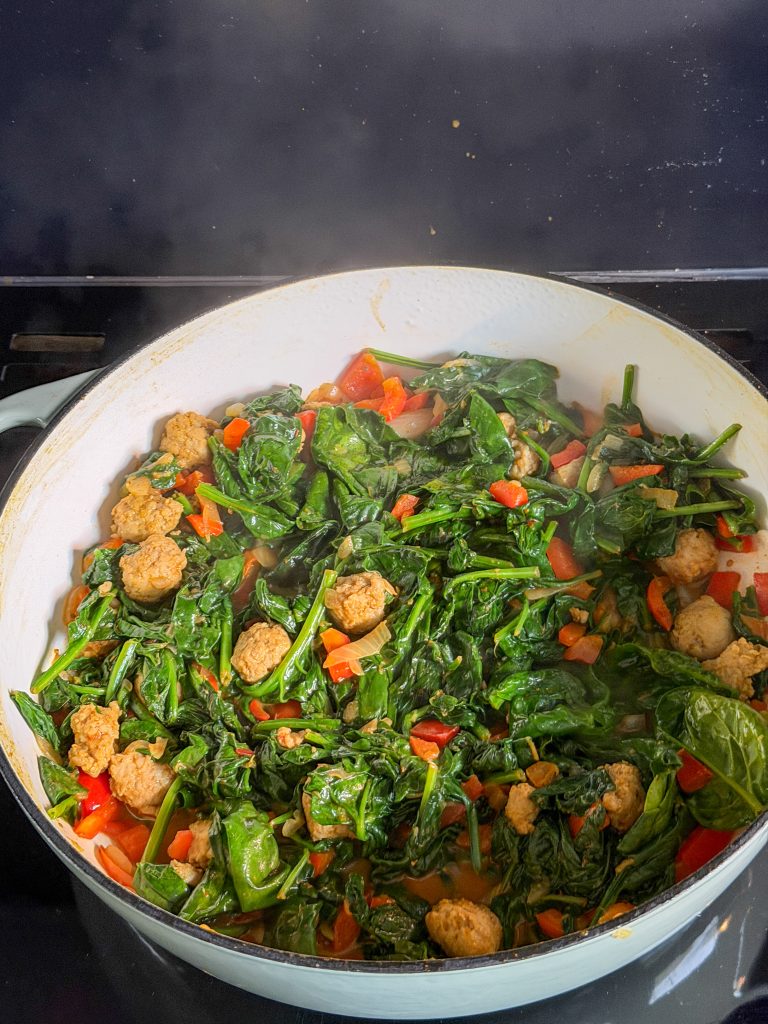 Spinazie toevoegen aan de pan met paprika en worst