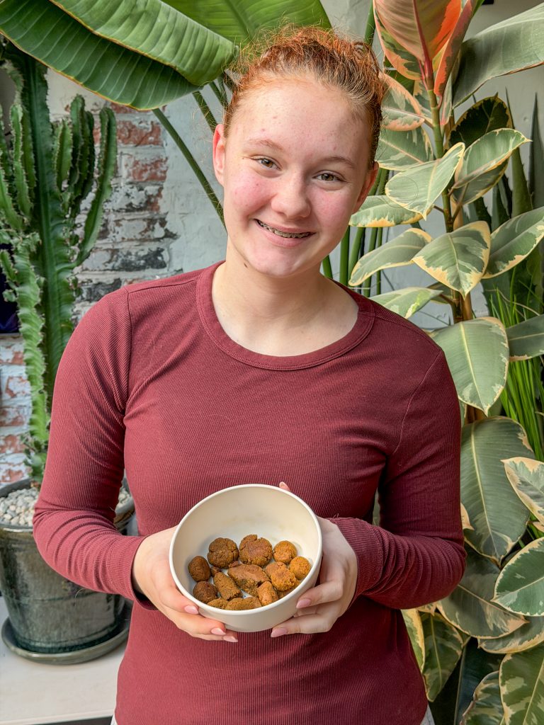 Amaranthe houdt een kom met zelfgemaakte hondensnoepjes vast in de keuken.