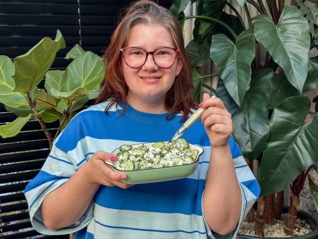 Beaudine houdt een schaaltje komkommer salade met feta vast voor het opscheppen