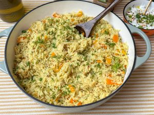 Eenpansgerecht met rijst en kip in vadouvan, geserveerd in grote pan met verse peterselie