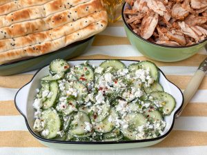 Komkommer salade met feta in een groen schaaltje van bovenaf, bestrooid met chilivlokken