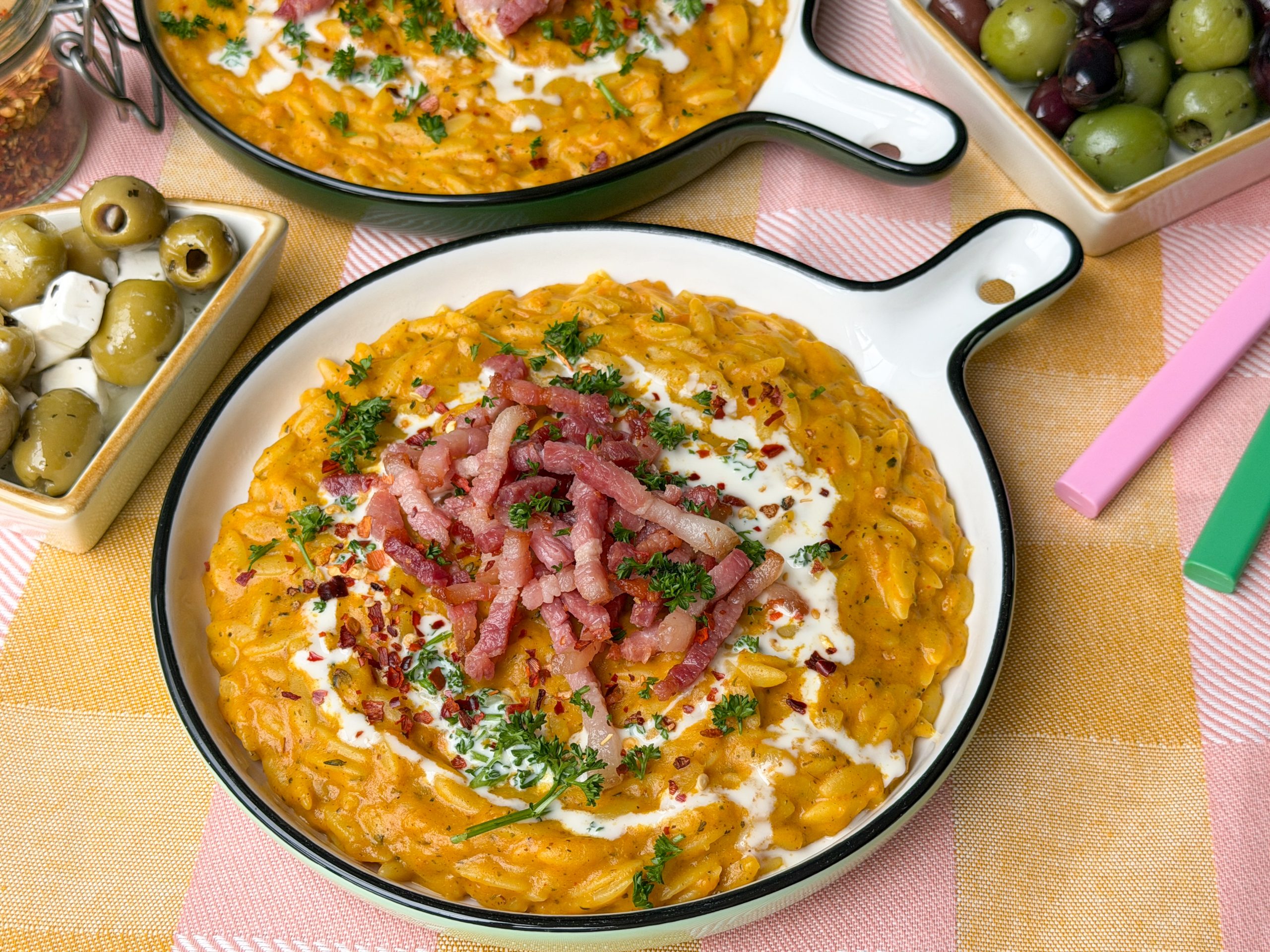 orzo met pompoen, romig eenpansgerecht met spekjes en kruiden op bord
