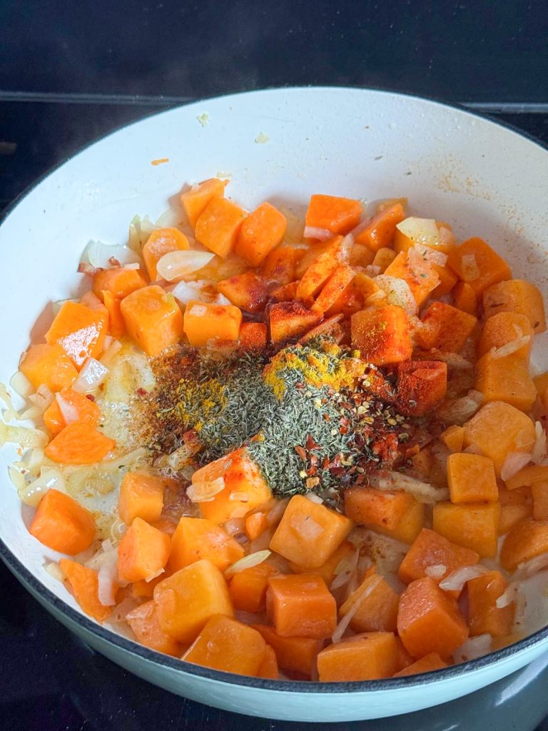 Gedroogde kruiden, specerijen en knoflook toevoegen aan de pompoen