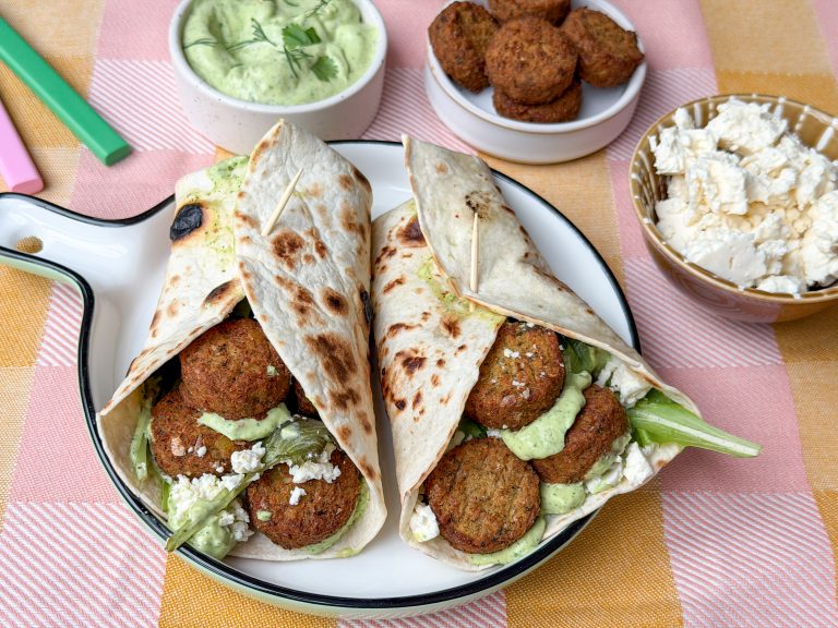 wraps gevuld met falafel, avocado yoghurtdip saus en feta op rond bord