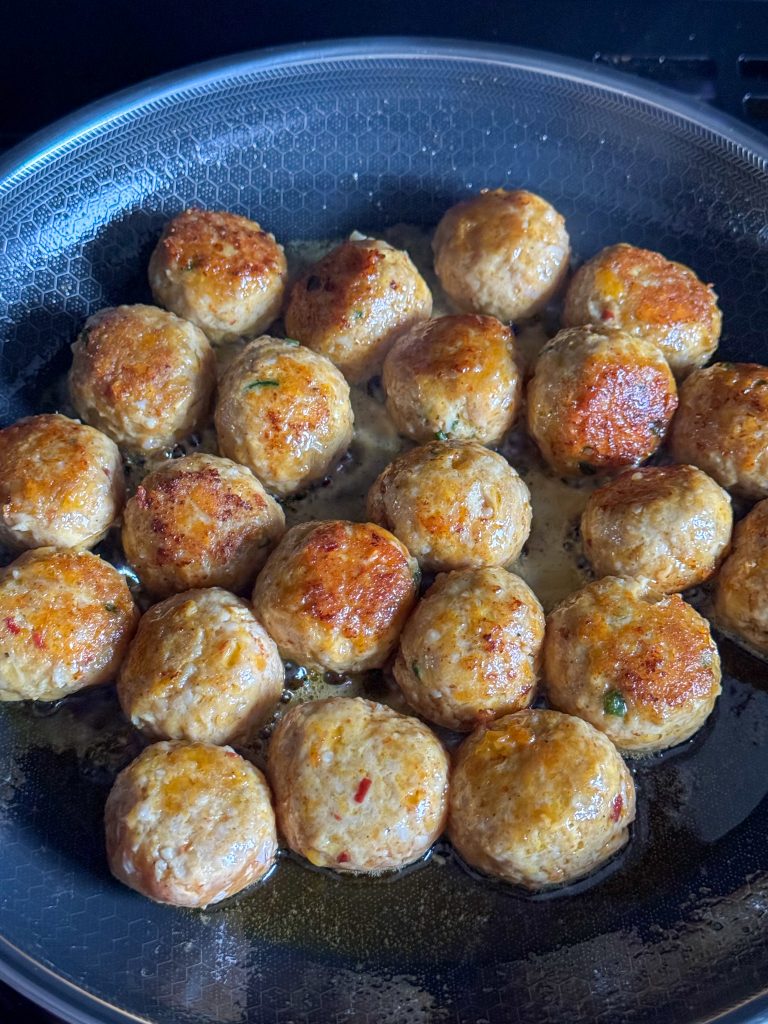 Goudbruin gebakken gehaktballetjes in de pan tijdens garen