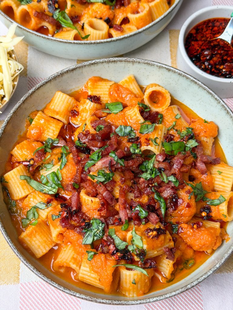 Romige pasta in kom met krokante spekjes en verse basilicum