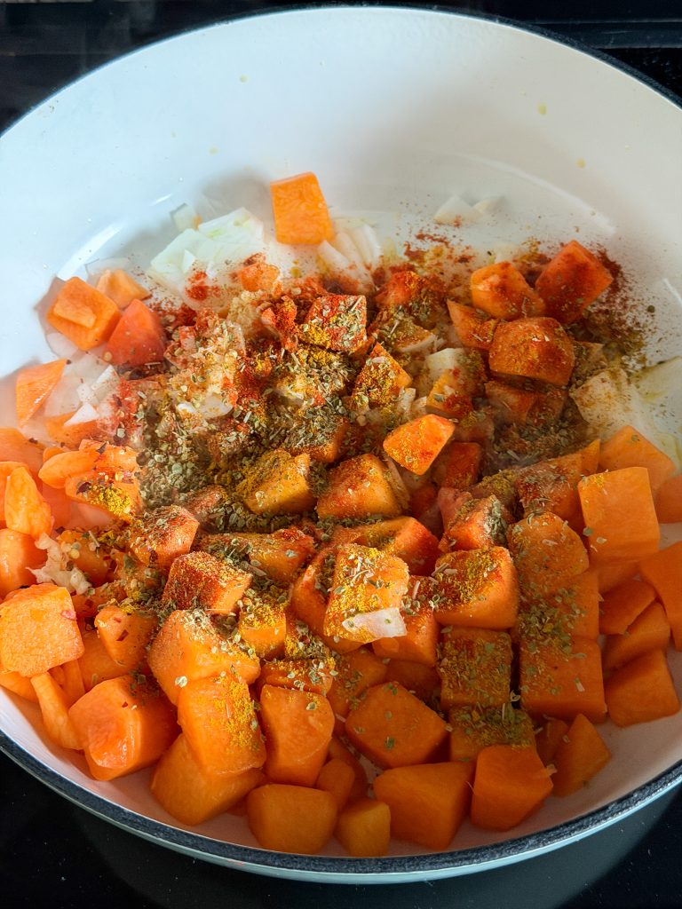 pompoenblokjes met ui en kruiden in de pan om aan te bakken