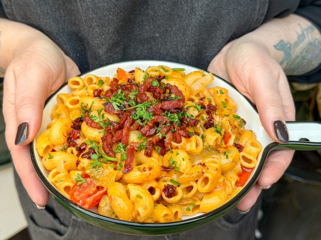 Handen houden bord pasta witlof vast