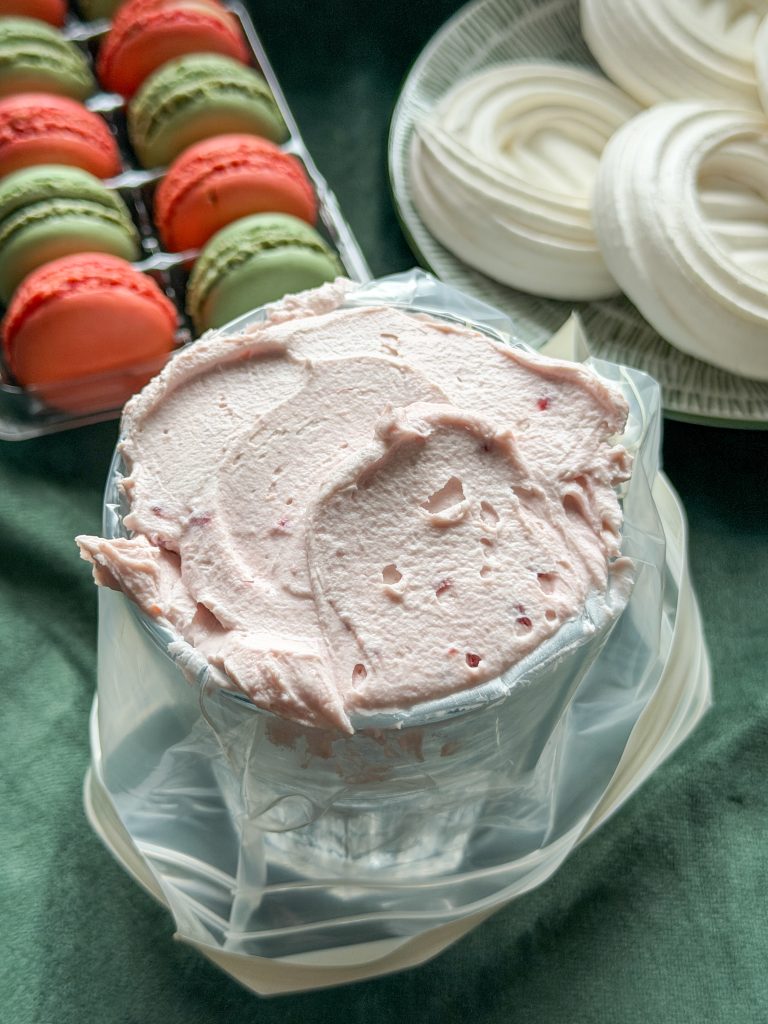 Macarponecrème in een spuitzak geschept met behulp van een glas