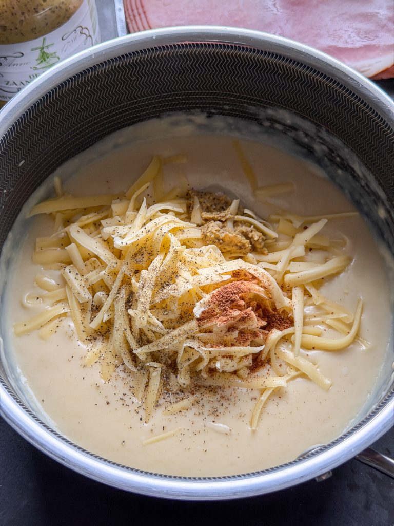 kaas, mosterd en kruiden door de bechamelsaus mengen